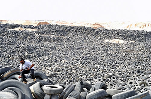 Man climbing over alandscape of old disposed tyres