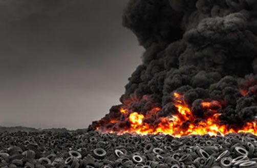 A field of worn tyres burns furiously producing a plume of black smoke